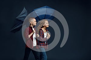 Boy and girl with umbrellas in studio, wind effect