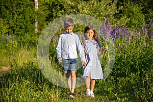 A boy and a girl walk across the field holding hands.