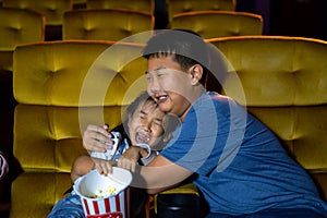 Boy and girl watching movie feeling scary and frightening at movie theater seats. The faces have feeling bad during film