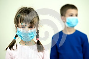 Boy and girl wearing blue protective medical mask ill with chickenpox, measles or rubella virus with rashes on body. Children