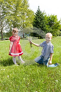 Boy gives a flower to girl. kids play outdoors