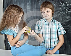 Boy gives a girl an apple at school