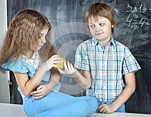 Boy gives a girl an apple at school