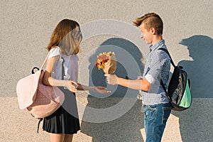 Boy gives girl bouquet of flowers. Outdoor portrait of couple teenagers