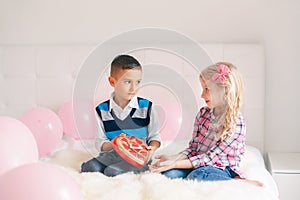 Boy giving girl chocolate gift present to celebrate Valentine Day