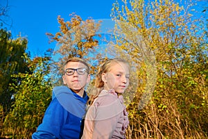 A boy with glasses next to a girl in the fall in the park, a young friendship and affection