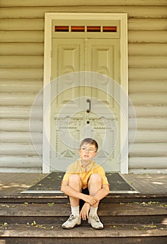 Boy in glasses seat on doorstep