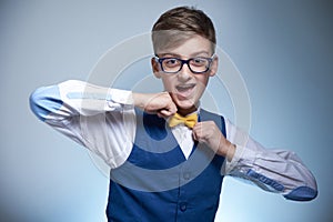 Boy with glasses and a shirt straightens a bow tie