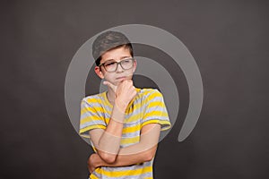 boy with glasses. thoughtful look. on a dark gray background.