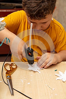 A boy glues snowflakes on a Christmas tree