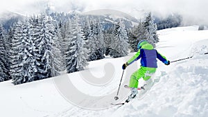 Boy go off piste ski downhill with beautiful snow forest on back