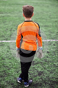 Boy goalkeeper stands in goal box on sports photo