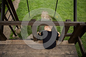 The boy goes through an obstacle course, goes in for active sports, sits on the edge of a wooden fence