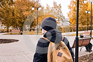 Boy goes to school wearing protective mask during the coronavirus pandemic. New normal. Back view