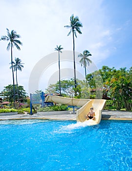 Boy going down the slide at swimming pool