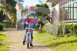 Boy going to school on bike. Kids ride bicycle