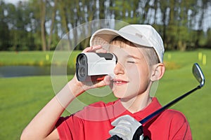 Boy golfer watching into rangefinder photo