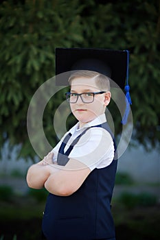 The boy is a graduate of elementary school in a graduate hat