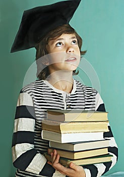 Boy in graduation cap with book pile