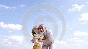 Boy grandchild make grandfather laugh touching old mans grey beard sky-high, hugging