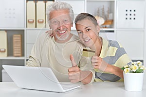 boy and grandfather with a laptop and credit card