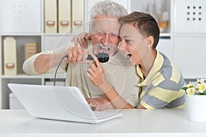 Boy and grandfather singing karaoke with with a laptop