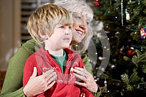 Boy on grandmother's lap by Christmas tree