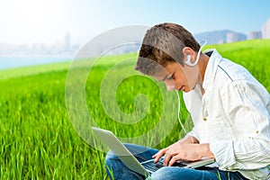 Boy in grass field with city background.