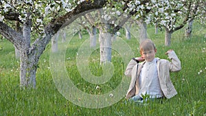 Boy on the grass near blooming apple trees in the garden