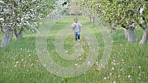 Boy on the grass near blooming apple trees in the garden