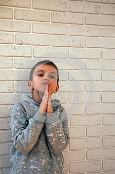 A boy in gray clothes with a gesture of begging for something