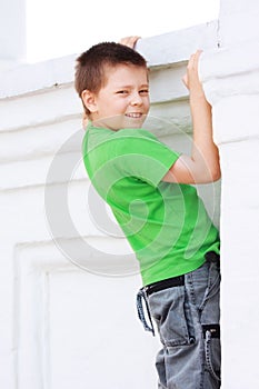 Boy in green climbing on wall