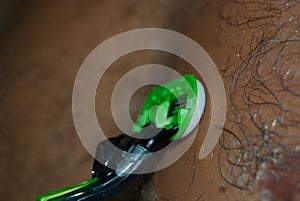 Boy with a green razor cutting his hair on chest