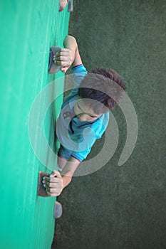 Boy gripping climbing holds on wall