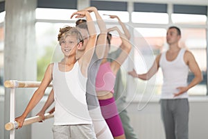 Boy during group class perform third position under male teacher guidance.