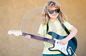 Boy with guitar. Child plays a guitar and sings, kids music and song. Funny little hipster musician child playing guitar