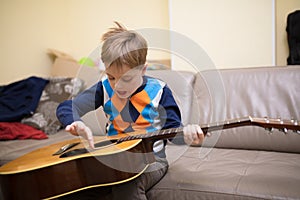 Boy with guitar sitting on couch