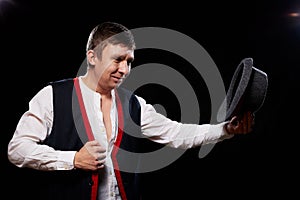 Boy or guy in national ethnic clothing posing in Studio on black background. Young man with hat in dark room