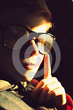 A boy with half-lighted face looking to the camera. Boy`s face in the sunset light.