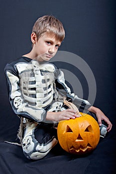 Boy in Halloween costume with orange pumpkin