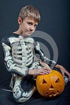 Boy in Halloween costume with orange pumpkin