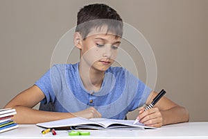 Boy hand holding pen in left hand and writing in a notebook, doing homework. Left Handers Day