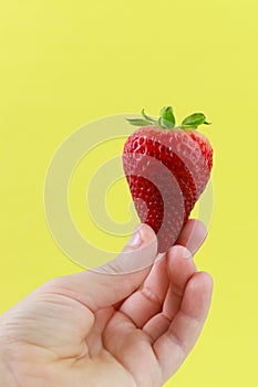 A boy hand holding a strawberry