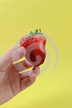 A boy hand holding a strawberry