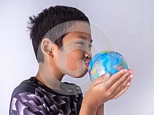 A boy hands the globe and kisses it on the globe. Show the power of the new generation to continue to develop our world