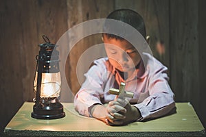 Boy hands holding a holy cross praying to God In the dark and with the lamp beside, Child Praying for God Religion
