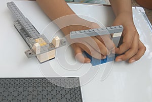 A boy  hands making a toy with plastic lego blocks.
