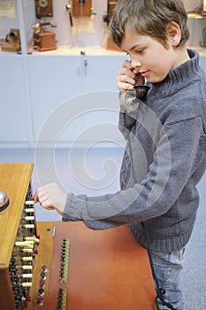 Boy with handset stands about old telephone