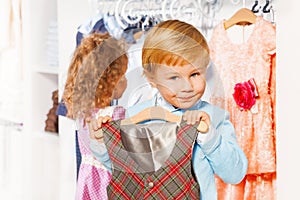 Boy with hanger and vest, girl choosing clothes