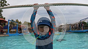 Boy hanging on a rope in water playground in aqua park